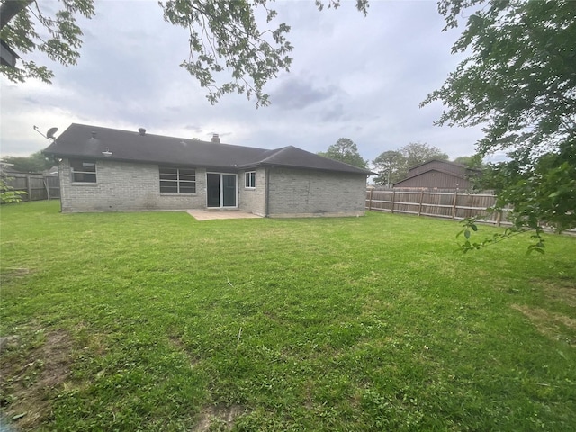 back of house with a lawn, a patio area, a fenced backyard, and brick siding