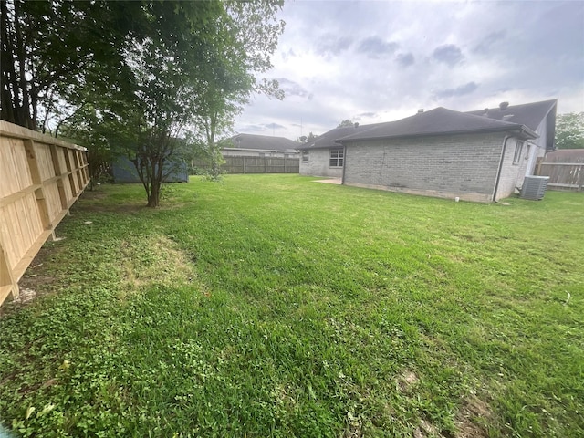view of yard with a fenced backyard and central AC unit