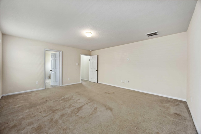 carpeted spare room featuring baseboards and visible vents