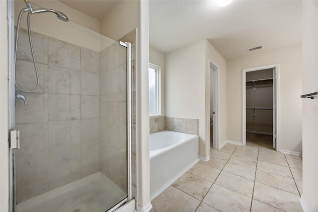 full bath with tile patterned floors, a stall shower, a bath, a walk in closet, and visible vents