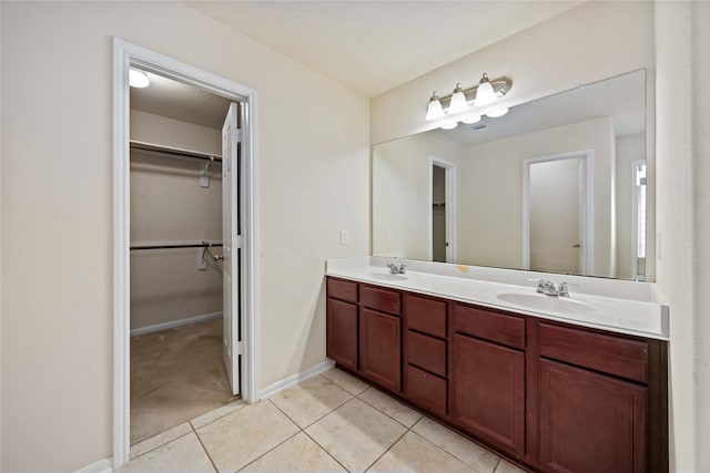 bathroom with a spacious closet, tile patterned floors, a sink, and double vanity