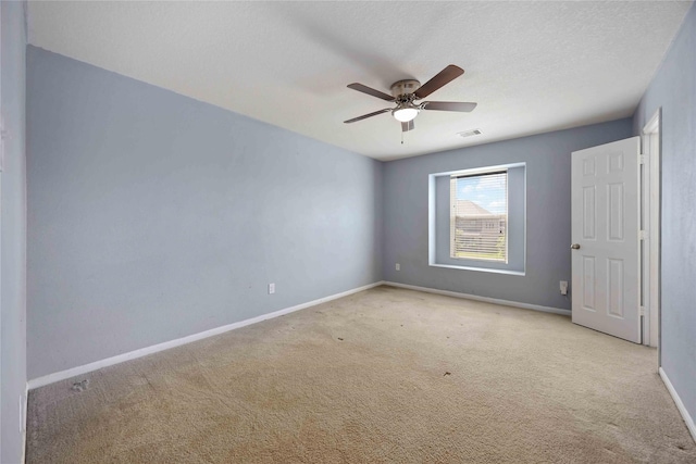 carpeted empty room featuring baseboards, a ceiling fan, and visible vents