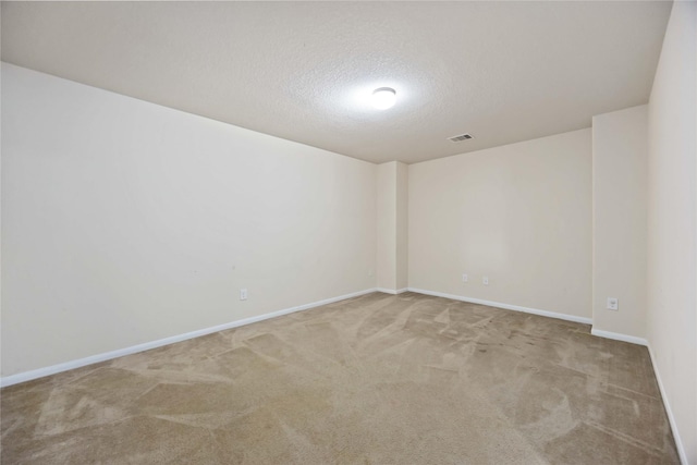 carpeted spare room with a textured ceiling, baseboards, and visible vents