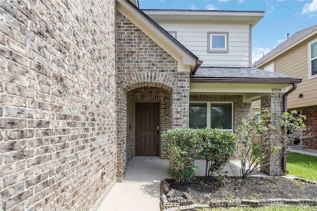 9939 Chimney Swift Ln, Conroe, TX 77385 - property entrance with brick siding, a shingled roof, and covered porch
