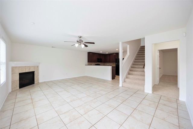 9939 Chimney Swift Ln, Conroe, TX 77385 - unfurnished living room with light tile patterned floors, a tile fireplace, a ceiling fan, stairs, and recessed lighting
