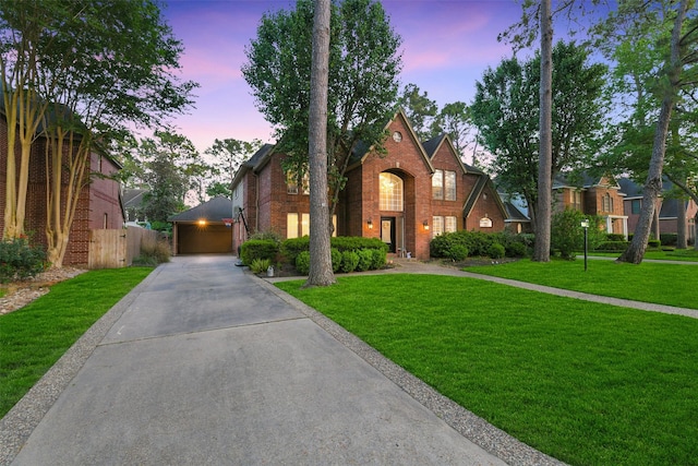 english style home with brick siding, driveway, a front yard, and fence