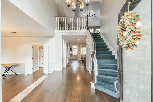 entrance foyer featuring wood finished floors, stairs, a high ceiling, a notable chandelier, and visible vents