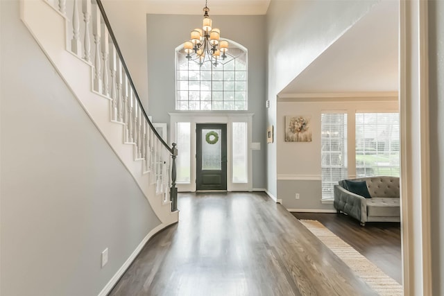 entrance foyer with a high ceiling, an inviting chandelier, wood finished floors, and plenty of natural light
