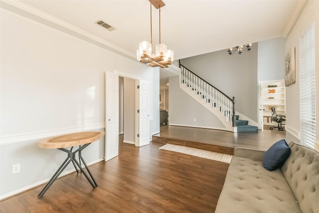 living area featuring an inviting chandelier, wood finished floors, visible vents, and stairs