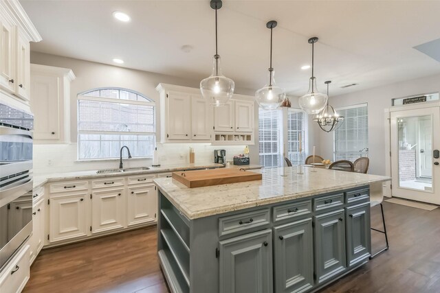 kitchen featuring recessed lighting, dark wood-style floors, gray cabinets, a sink, and a kitchen island