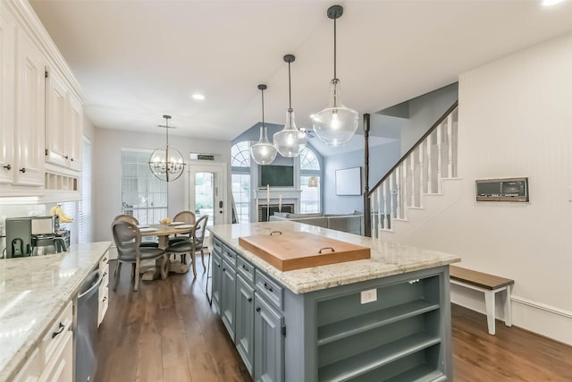 kitchen featuring a chandelier, dark wood finished floors, a kitchen island, a fireplace, and white cabinetry