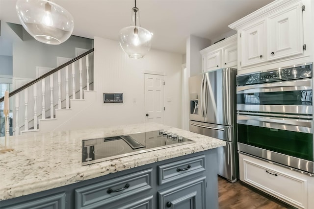 kitchen with dark wood finished floors, light stone counters, stainless steel appliances, decorative light fixtures, and white cabinetry