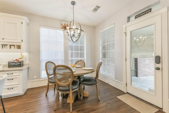 dining room with dark wood finished floors, an inviting chandelier, and visible vents