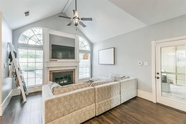 living area featuring dark wood finished floors, vaulted ceiling, visible vents, ceiling fan, and a fireplace