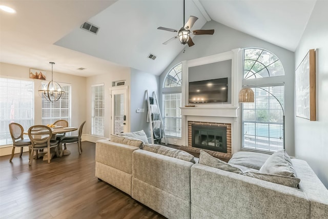 living room featuring dark wood finished floors, a fireplace, visible vents, and ceiling fan with notable chandelier
