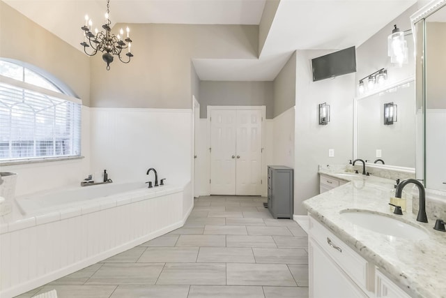full bathroom with two vanities, a garden tub, wainscoting, and a sink