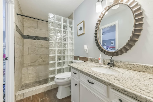 bathroom featuring wood finished floors, toilet, vanity, and a walk in shower
