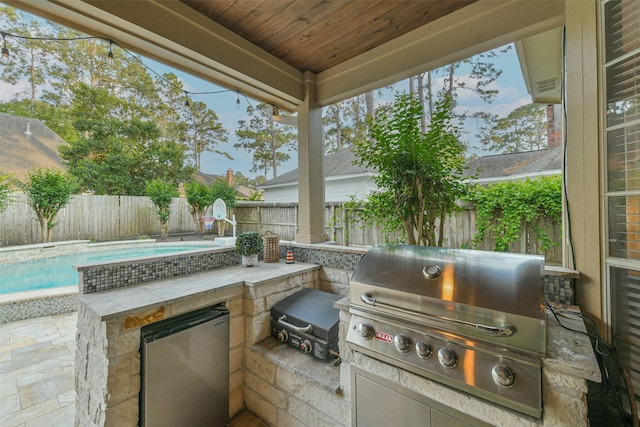 view of patio / terrace with grilling area, a fenced in pool, an outdoor kitchen, and a fenced backyard