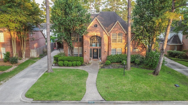 view of front facade with a front lawn, brick siding, and fence