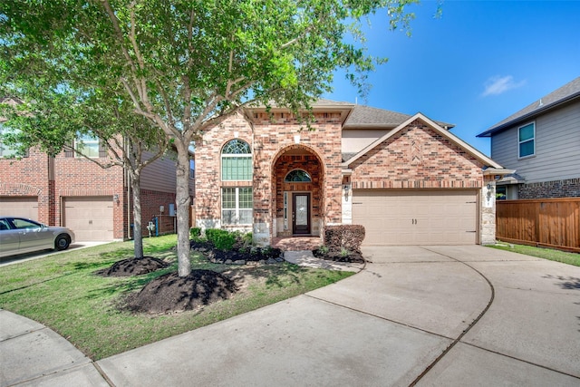 traditional-style house featuring a front yard, a garage, brick siding, concrete driveway, and fence