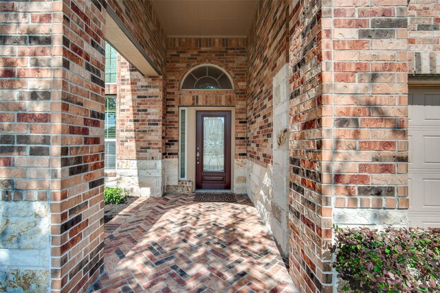 doorway to property with covered porch and brick siding