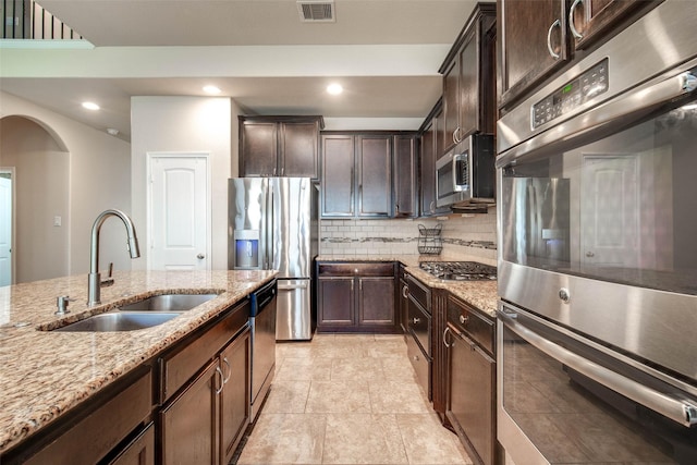 kitchen featuring tasteful backsplash, a sink, appliances with stainless steel finishes, visible vents, and arched walkways