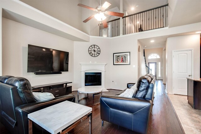 living room with a fireplace with raised hearth, hardwood / wood-style floors, recessed lighting, a ceiling fan, and high vaulted ceiling