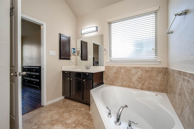 full bathroom featuring a bath, vaulted ceiling, and vanity