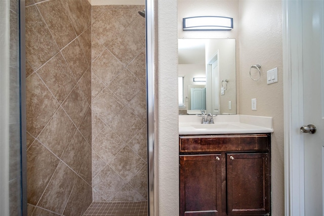 bathroom featuring a stall shower, a textured wall, and vanity