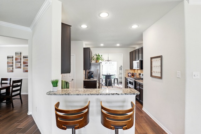 kitchen with stainless steel appliances, baseboards, ornamental molding, and dark wood finished floors