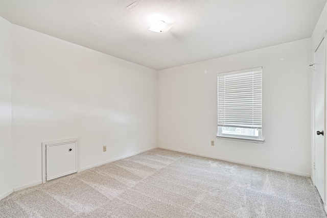unfurnished room with baseboards and light carpet