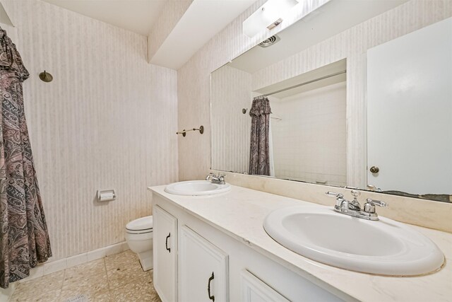 bathroom featuring a sink, toilet, and wallpapered walls