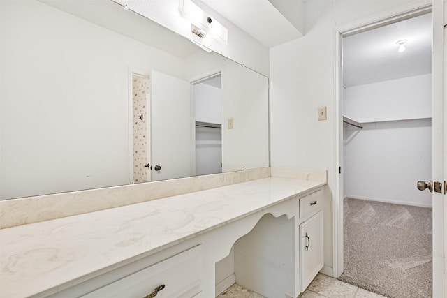 bathroom featuring a spacious closet and vanity