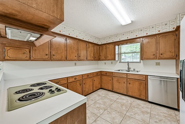 kitchen featuring brown cabinets, a sink, dishwasher, light countertops, and a textured ceiling