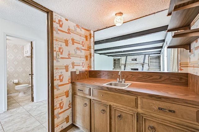 4206 Willow Hill Dr, Seabrook, TX 77586 - kitchen with a textured ceiling, brown cabinets, a sink, light tile patterned floors, and wallpapered walls