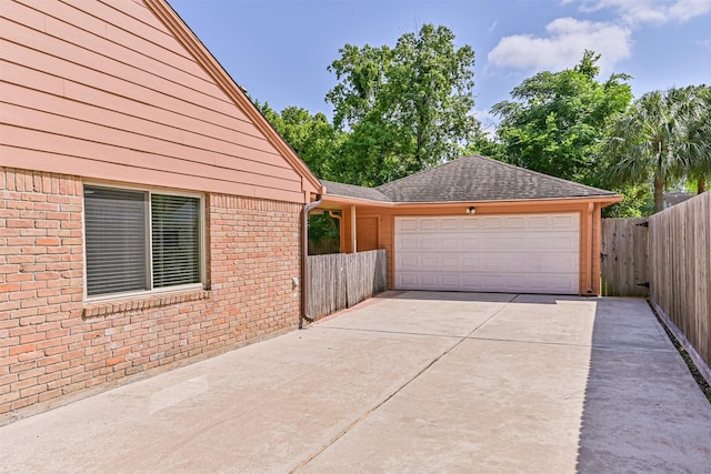 exterior space with brick siding, fence, driveway, and a garage