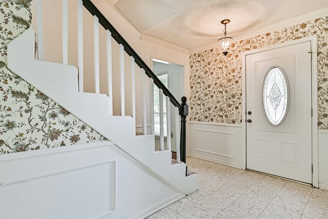 entryway with plenty of natural light, ornamental molding, stairs, and a wainscoted wall