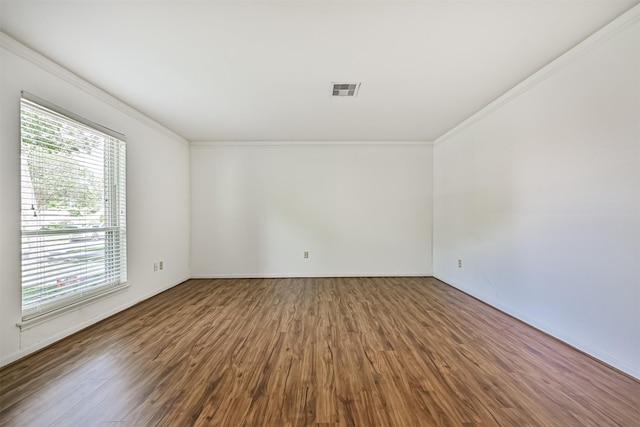 unfurnished room featuring crown molding, baseboards, wood finished floors, and visible vents