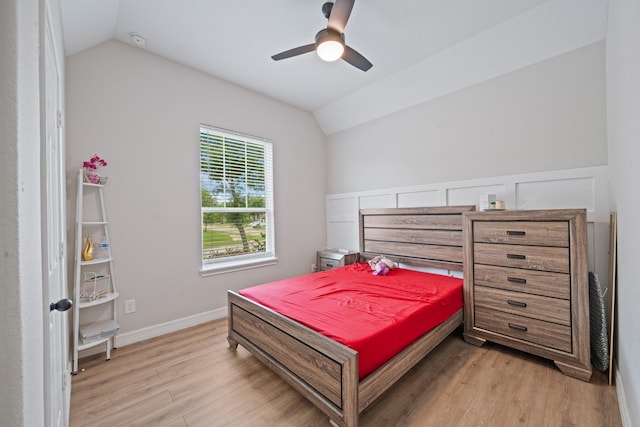 bedroom featuring vaulted ceiling, a ceiling fan, baseboards, and light wood-style flooring