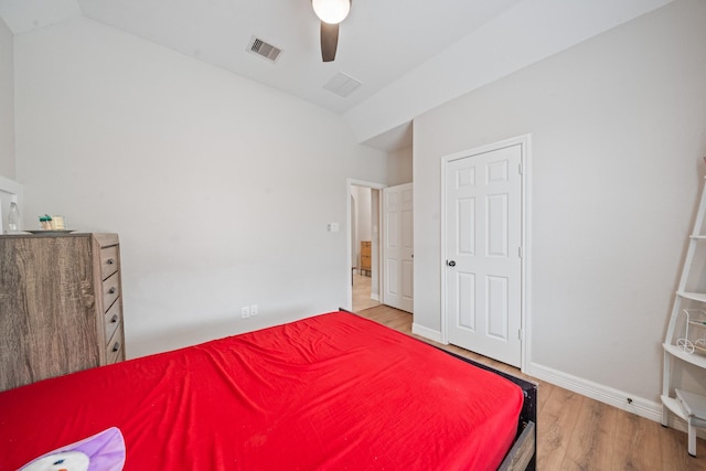 bedroom featuring vaulted ceiling, a ceiling fan, wood finished floors, and visible vents