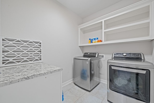 laundry area featuring washing machine and dryer, baseboards, light tile patterned flooring, and laundry area