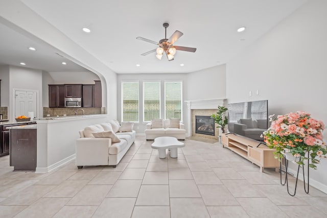 living room with recessed lighting, a ceiling fan, light tile patterned floors, arched walkways, and a fireplace
