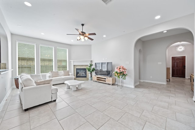 living area with arched walkways, a ceiling fan, light tile patterned flooring, and recessed lighting