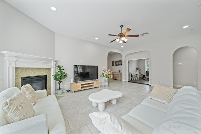 tiled living room featuring a tiled fireplace, arched walkways, visible vents, and recessed lighting