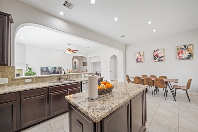 kitchen featuring a peninsula, arched walkways, a sink, visible vents, and recessed lighting