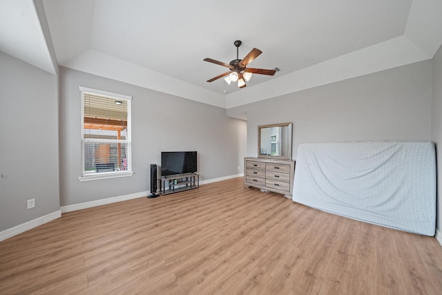 interior space featuring baseboards, wood finished floors, a tray ceiling, and ceiling fan