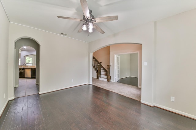unfurnished room with arched walkways, visible vents, stairway, ceiling fan, and hardwood / wood-style floors
