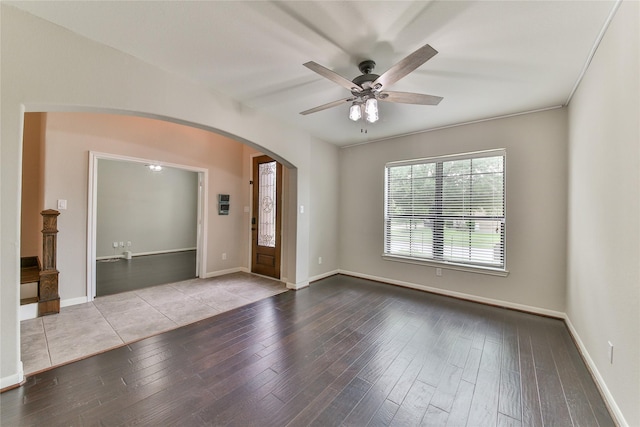unfurnished room with wood-type flooring, arched walkways, ceiling fan, and baseboards