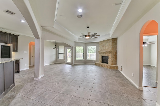 unfurnished living room with ceiling fan, a fireplace, visible vents, and a raised ceiling
