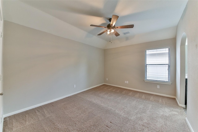 carpeted spare room featuring arched walkways, ceiling fan, baseboards, and visible vents